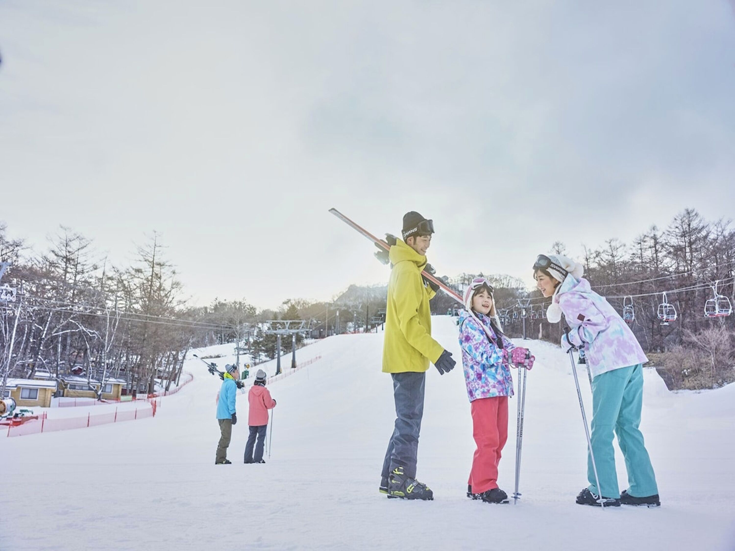 A group of people on a snowy slope with ski lifts in the background.