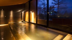 Área de piscina interna moderna com vista para árvores.