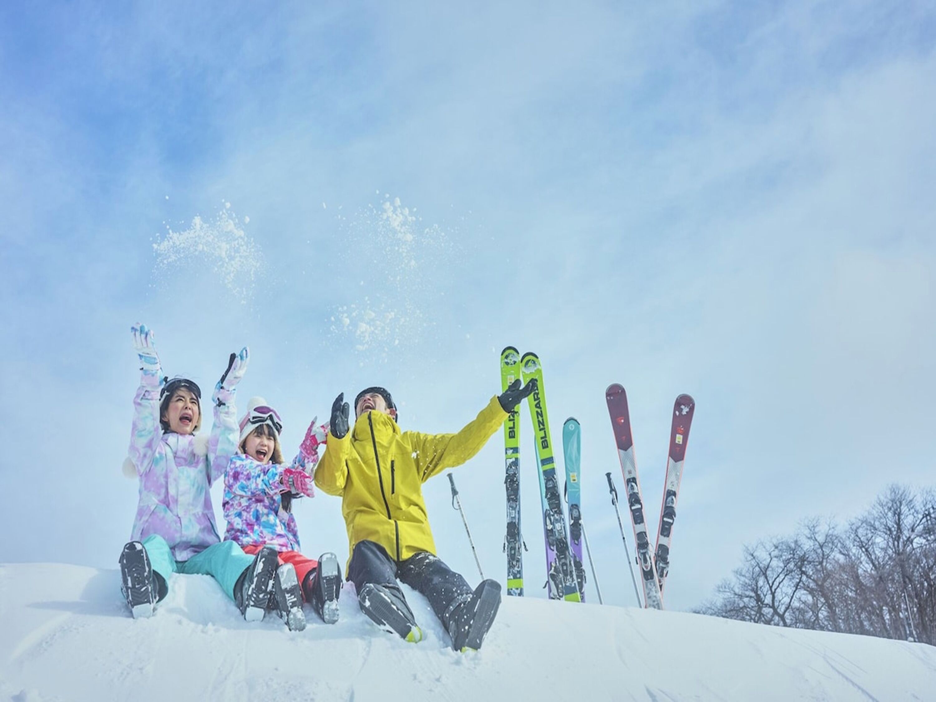 Un groupe de personnes est assis sur une pente enneigée, leurs skis étant alignés derrière eux.