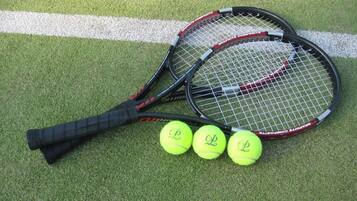 Two tennis rackets and three tennis balls on a green surface with white lines.