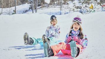 Two children sledding on a snowy slope.