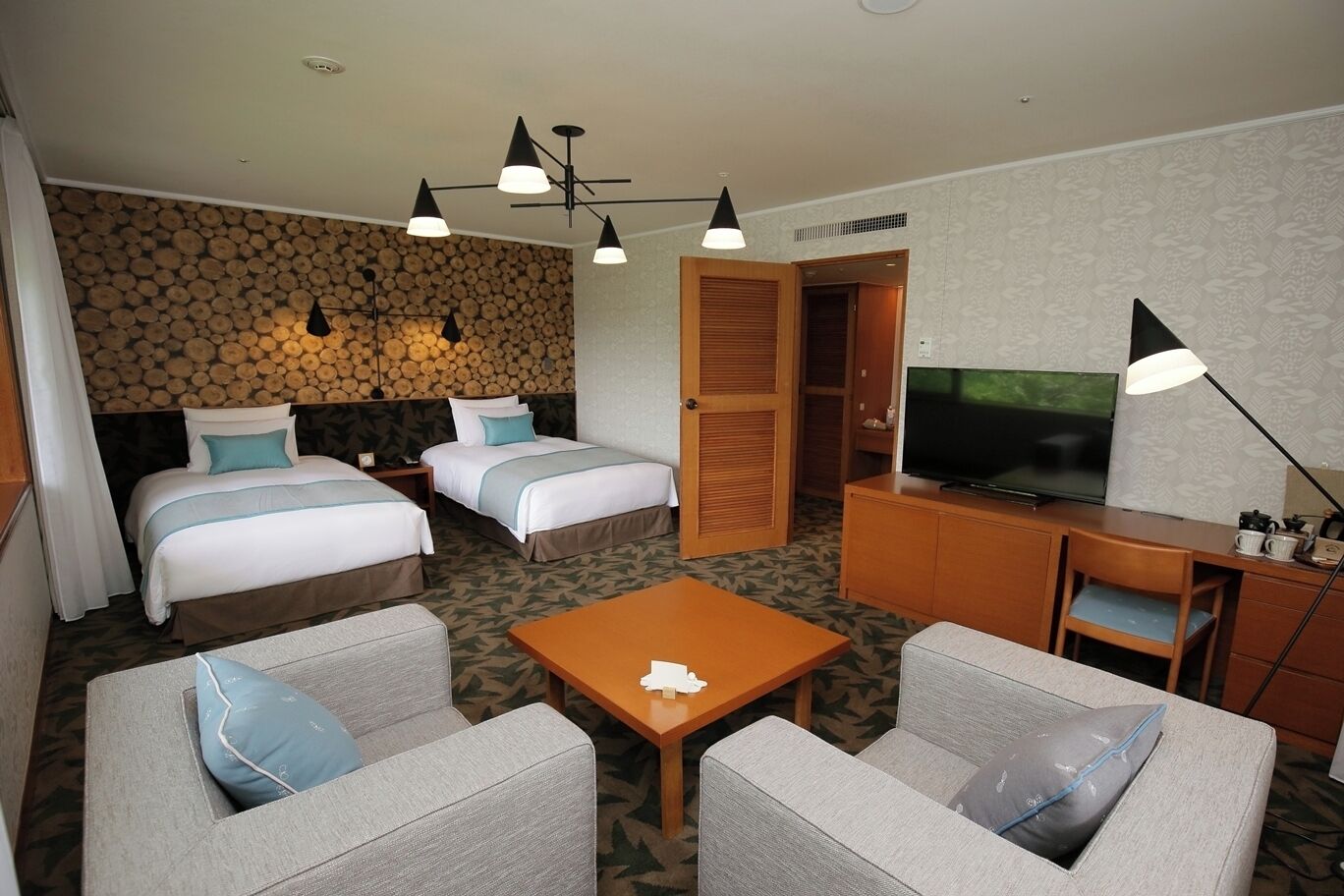 Une chambre d’hôtel avec deux lits, une télévision, un bureau et un coin salon.