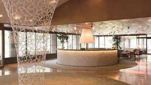 A spacious lobby with a central reception desk, large windows, and a decorative hanging structure. - Karuizawa Prince Hotel East (Karuizawa)