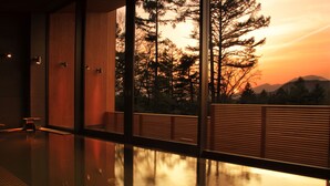A modern building with large windows reflecting a sunset and trees. - Karuizawa Prince Hotel East (Karuizawa)