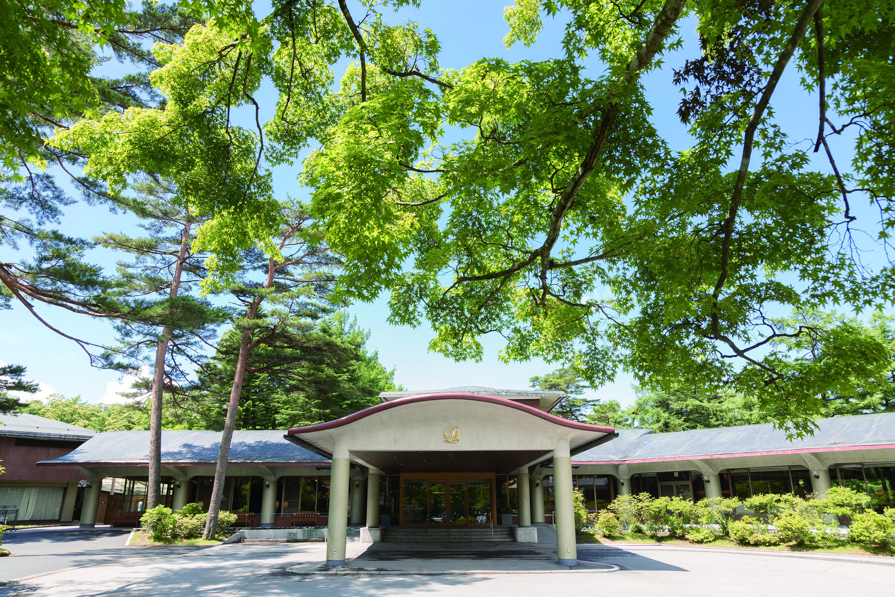 A building with a covered entrance, surrounded by trees and a clear sky.