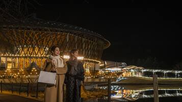 A modern building with a unique architectural design, featuring a large, curved structure and illuminated interior lights.