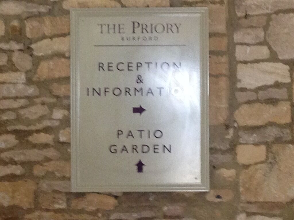 Wegwijzer voor The Priory in Burford, met aanduiding voor de receptie & informatie en de patio tuin.