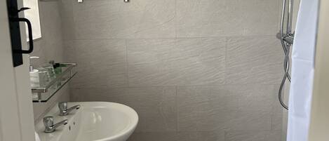 A bathroom with a white sink, a mirror, and a shower.