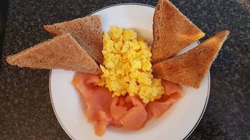 Un plato con huevos revueltos, salmón ahumado y tostadas triangulares.