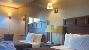 A hotel room with two beds, a nightstand, a lamp, and a mirror.