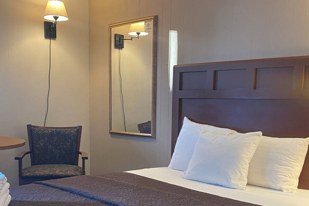 Una habitación de hotel con una cama grande, una silla, un escritorio y un espejo.