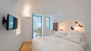 A bedroom with a bed, a mounted TV, a wall-mounted lamp, and a butterfly decoration.