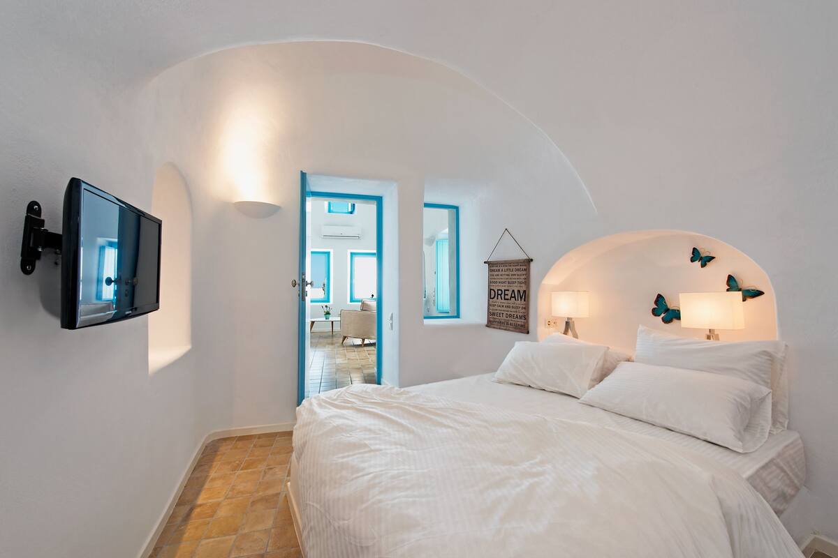 Une chambre à coucher avec un lit, un téléviseur fixé au mur, une lampe fixée au mur et une décoration en forme de papillon.
