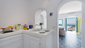 A modern kitchen with a sink, stove, and decorative items. It leads to a dining area with a view.