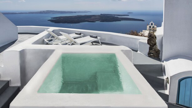 A white infinity pool with a view of the sea and islands.