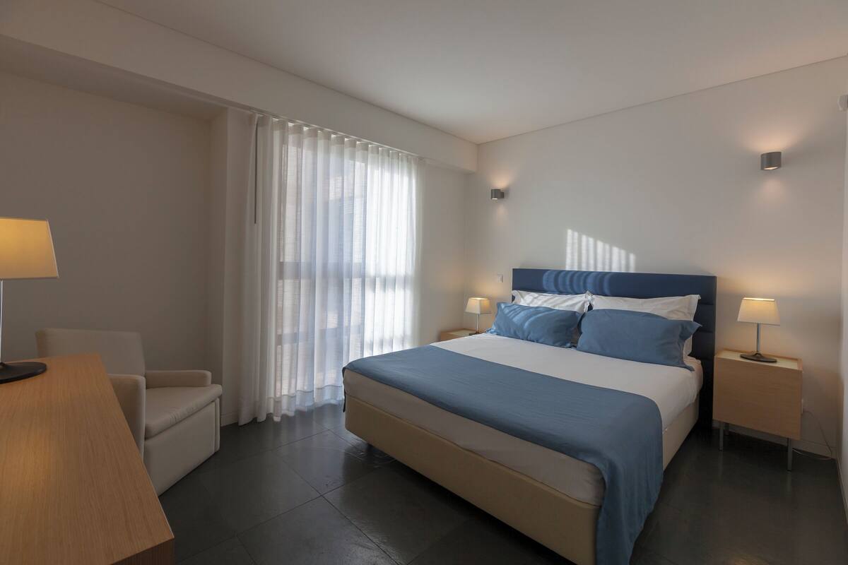 Een moderne hotelkamer met een groot bed, een bureau en een stoel.
