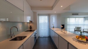 Eine moderne Küche mit Spüle aus Edelstahl, Backofen und einer Arbeitsplatte mit Obstschale.
