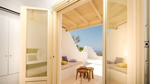 A modern bedroom with a glass door leading to a balcony with a view of the sea. - White Orchid Villa (Santorini)