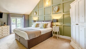 A bedroom with a large bed, a nightstand, a wardrobe, and a wall clock. - Broadrock (Chepstow)