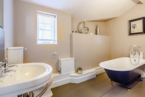 A bathroom with a white sink, a bathtub, and a window with blinds.