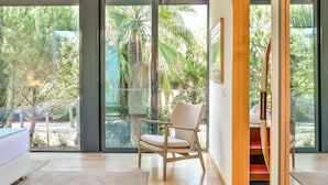 A modern room with large glass doors leading to a balcony, a wooden chair, and a bed. - Troia Residence Beach Houses (Grandola)