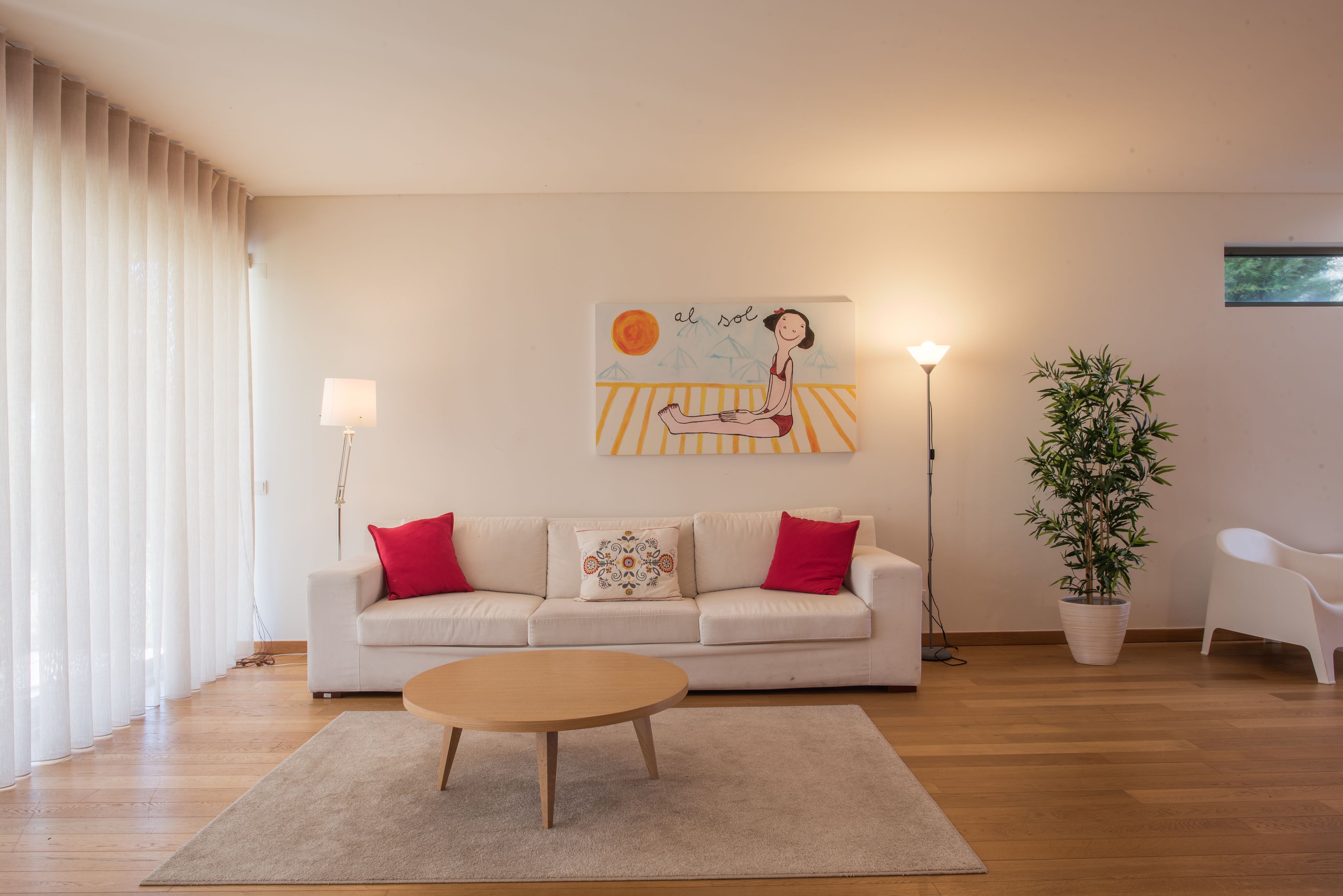 Una sala de estar con un sofá, una mesa de centro, una lámpara y un cuadro en la pared.