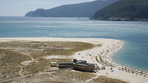 A coastal beach with a sandy shore, a few buildings, and a clear view of the sea. - Troia Residence Beach Houses (Grandola)
