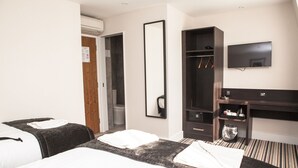 Habitació d'hotel amb dos llits, un armari, escriptori amb televisió i dutxes.