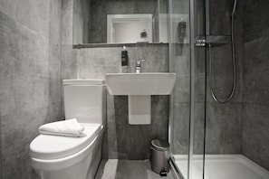A modern bathroom with a toilet, sink, and glass-enclosed shower.