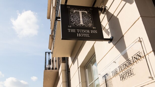 Cartell de l'Hotel The Tudor Inn, amb una 'T' destacada i detalls ornamentals.