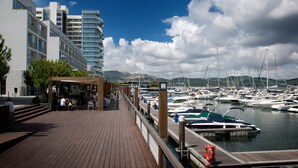 Un port de plaisance avec des bateaux amarrés, une terrasse en bois et des bâtiments modernes en arrière-plan.