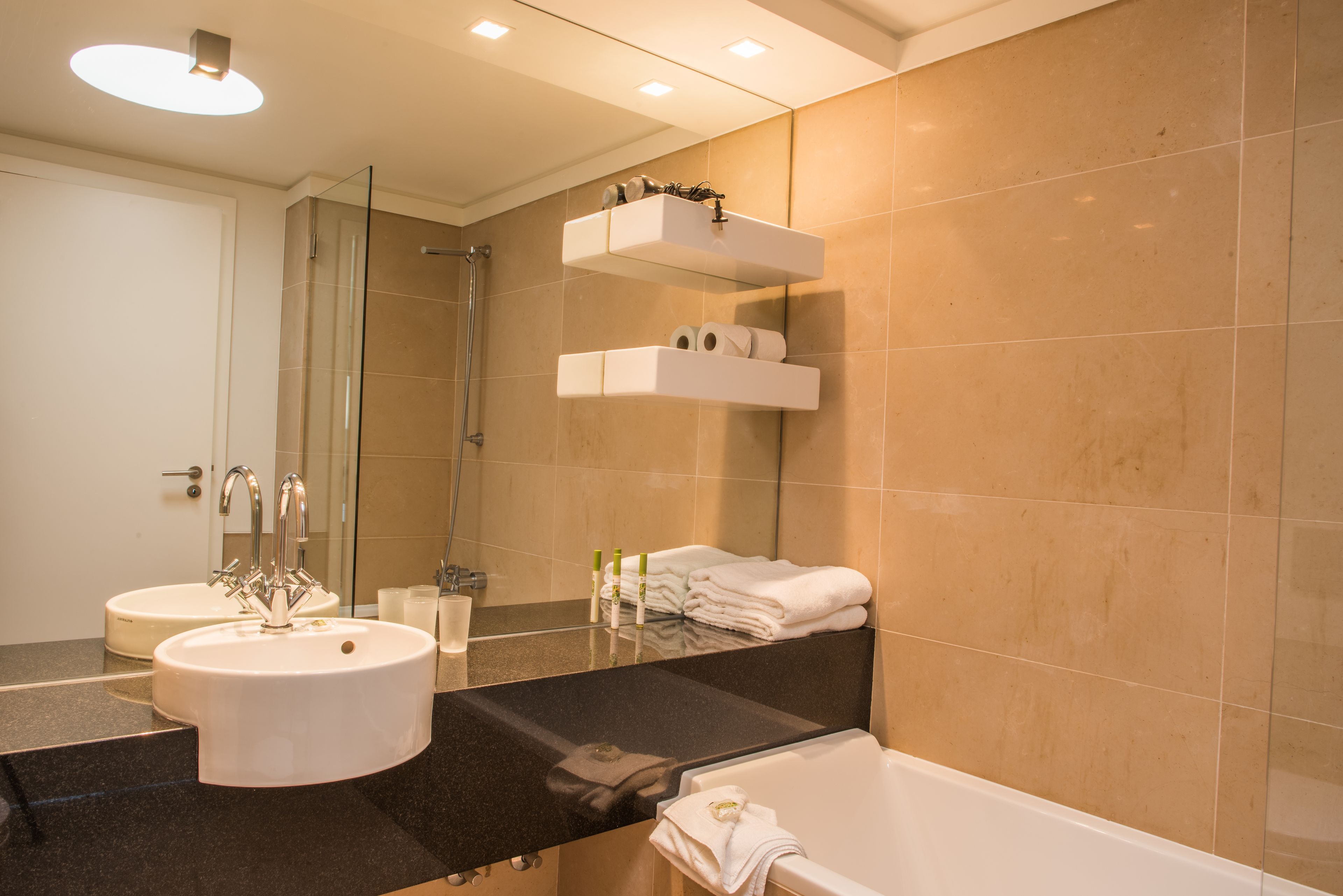 Ein modernes Badezimmer mit zwei Waschbecken, einer Duschkabine aus Glas und einer Badewanne.