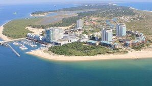 Une station balnéaire dotée de nombreux immeubles de grande hauteur, d’un port de plaisance avec des bateaux et d’une plage.