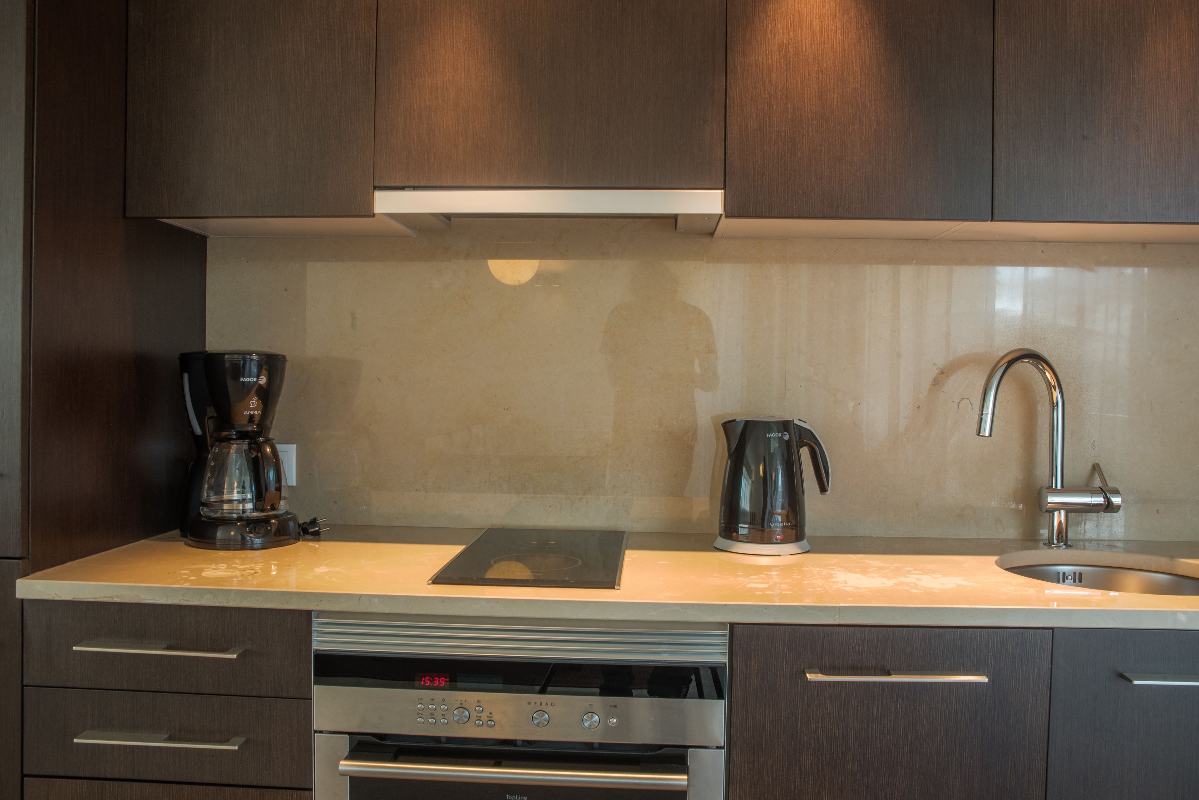 Een moderne keuken met een inbouwoven, koffiezetapparaat en waterkoker.