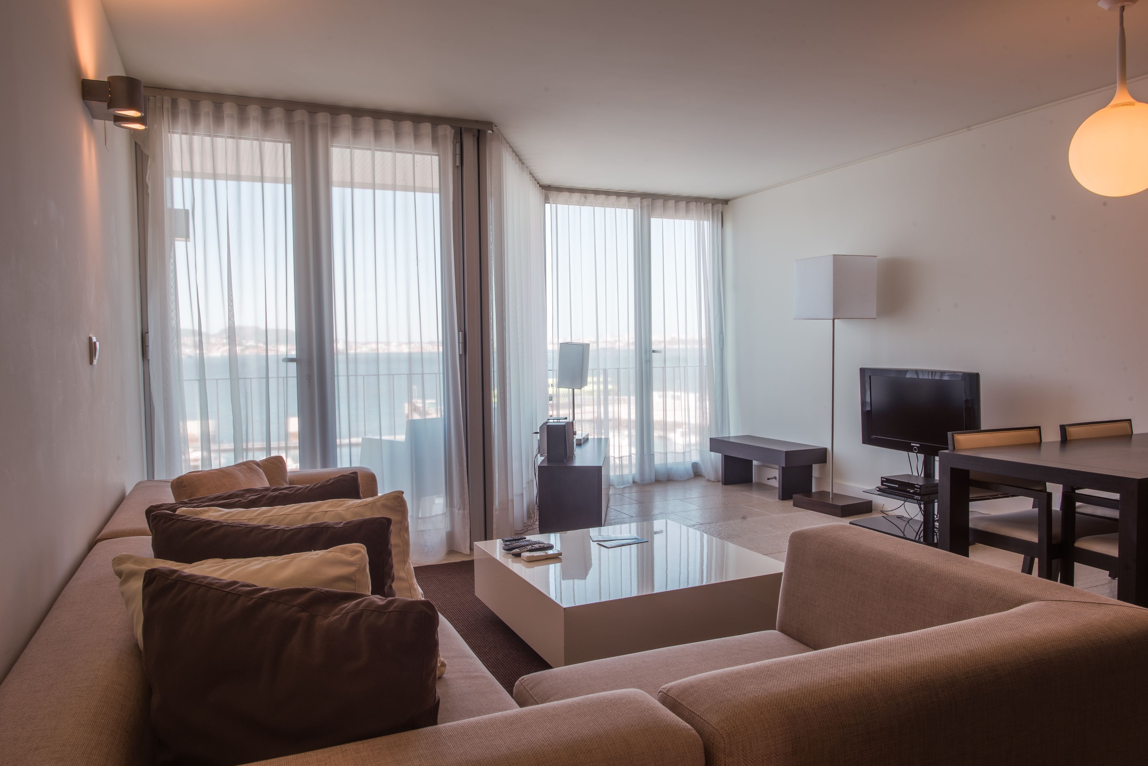 A modern living room with a sofa, coffee table, TV, and a balcony view.