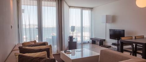 A modern living room with a sofa, coffee table, TV, and a balcony view.