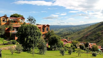 A hillside property with multiple buildings, lush greenery, and a scenic view of rolling hills.
