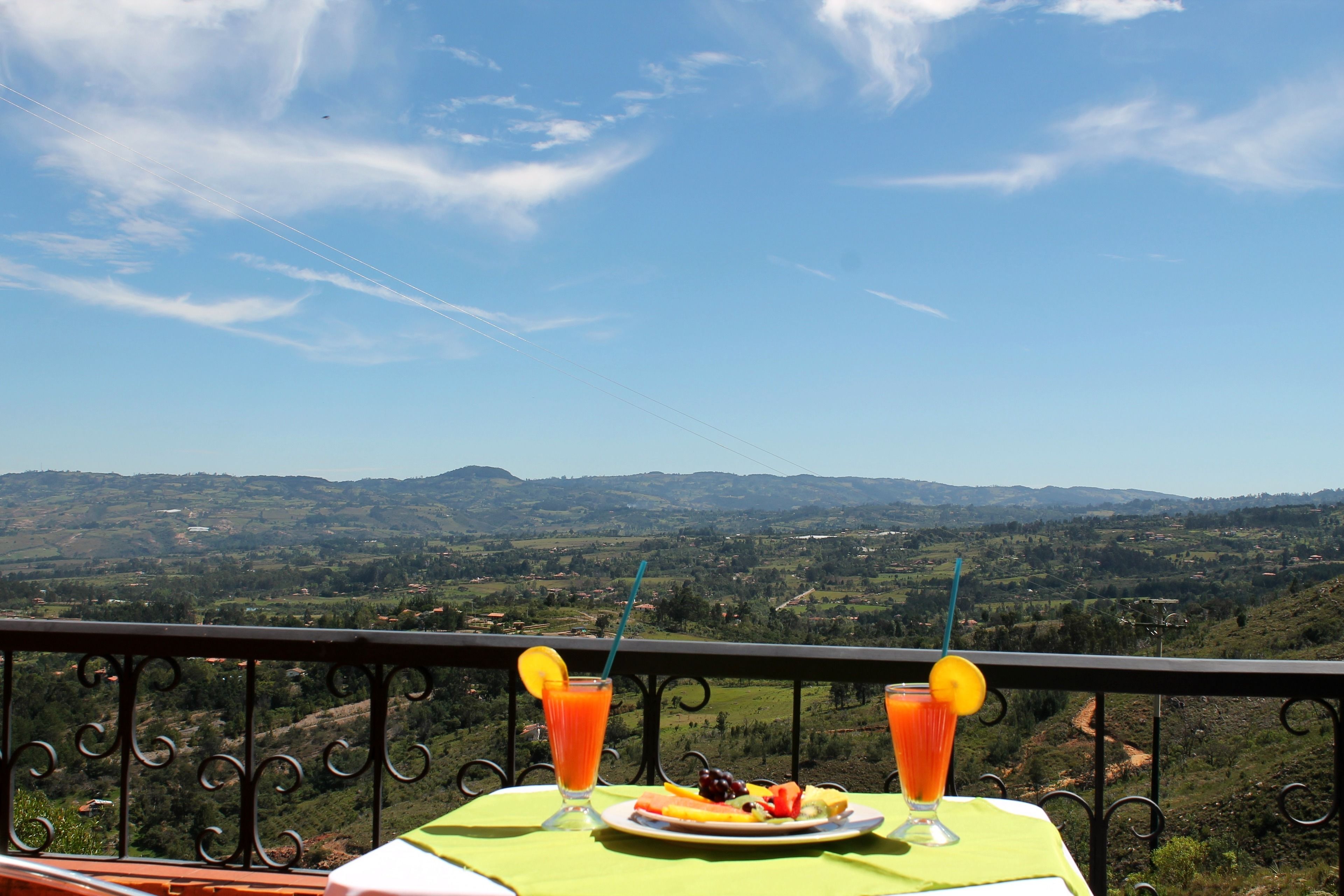 Une table sur le balcon, avec un repas et des boissons, offrant une vue sur un paysage magnifique.