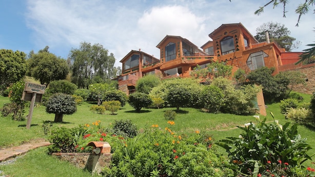 A large, multi-story building with a brick exterior and multiple balconies. - Suites Arcoiris (Villa de Leyva)