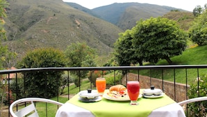 A table with breakfast items and a view of a mountainous landscape. - Suites Arcoiris (Villa de Leyva)