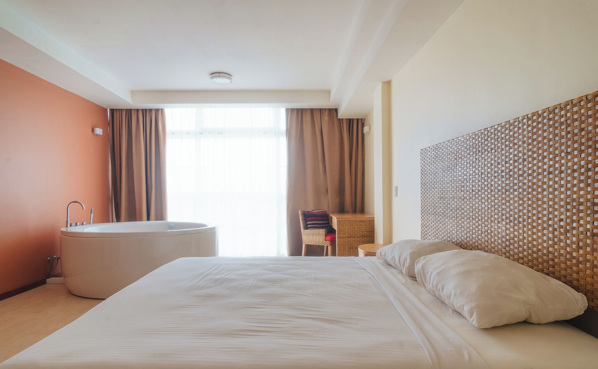 Une chambre d’hôtel avec un grand lit, une baignoire séparée, un fauteuil et une vue sur l’extérieur.