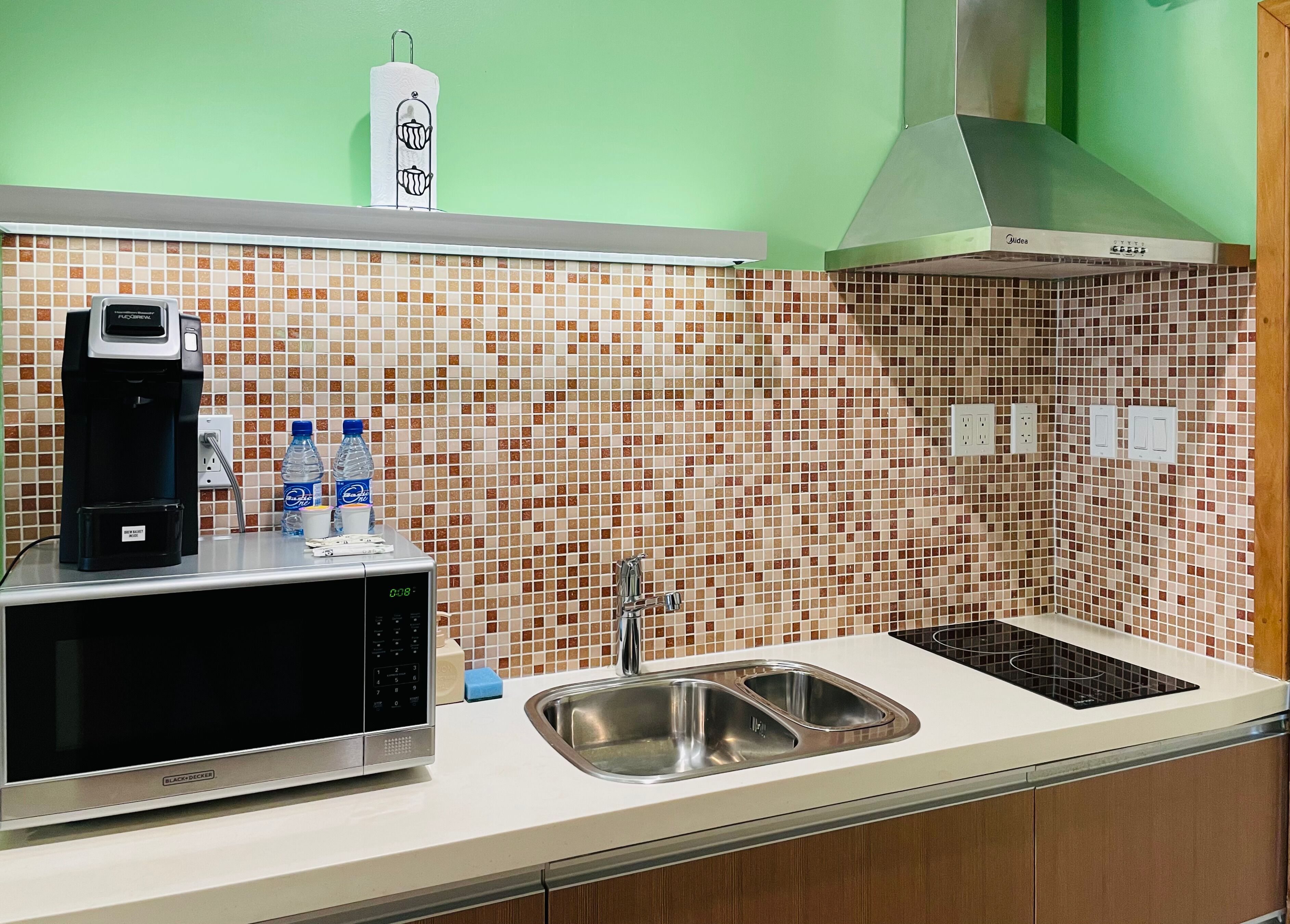 A kitchen with a microwave, coffee maker, and water bottles on the counter.