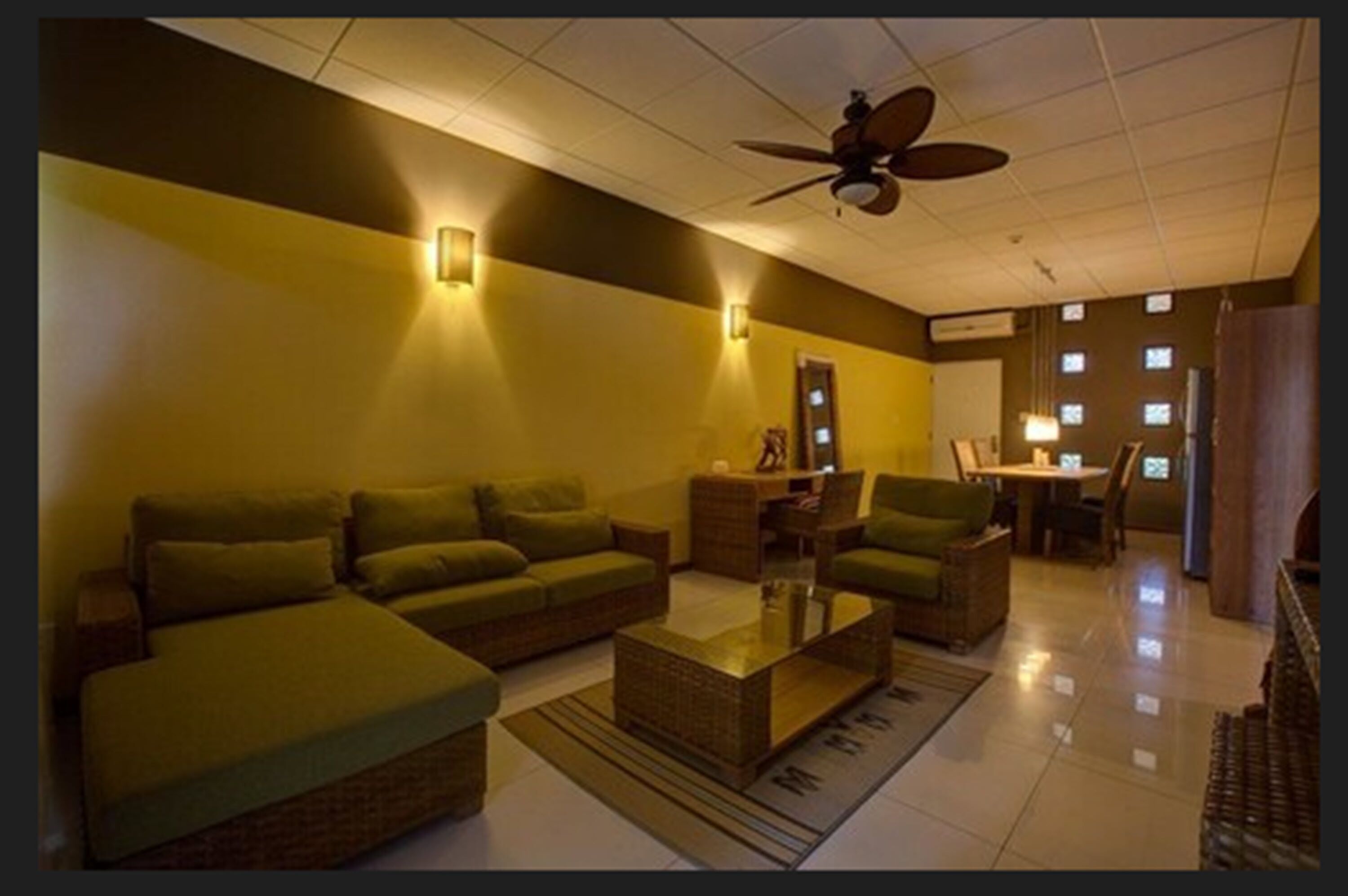 Sala de estar com sofá verde, mesa de centro e ventilador de teto.
