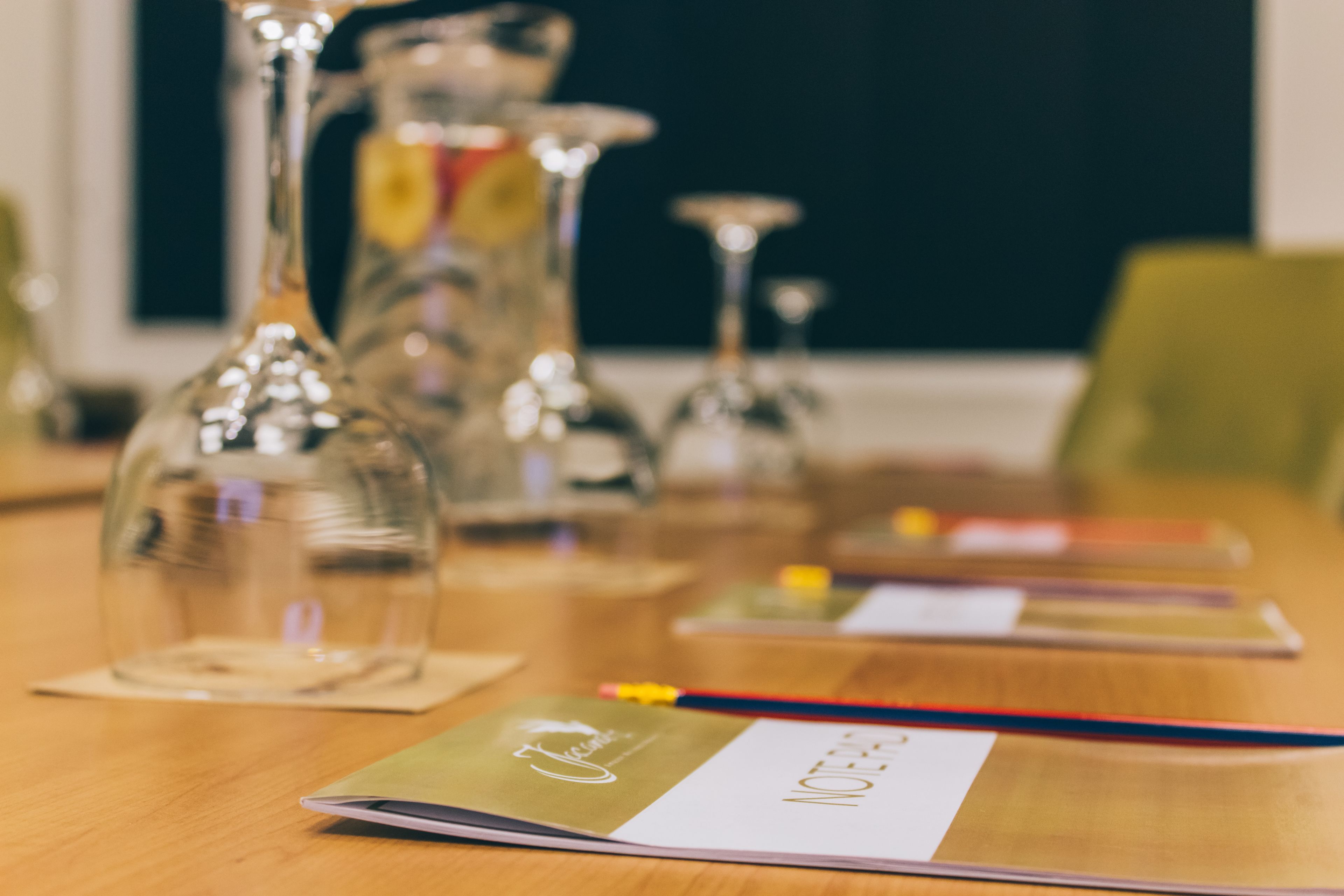 Een houten tafel met een notitieboekje, een pen en een glazen vaas.
