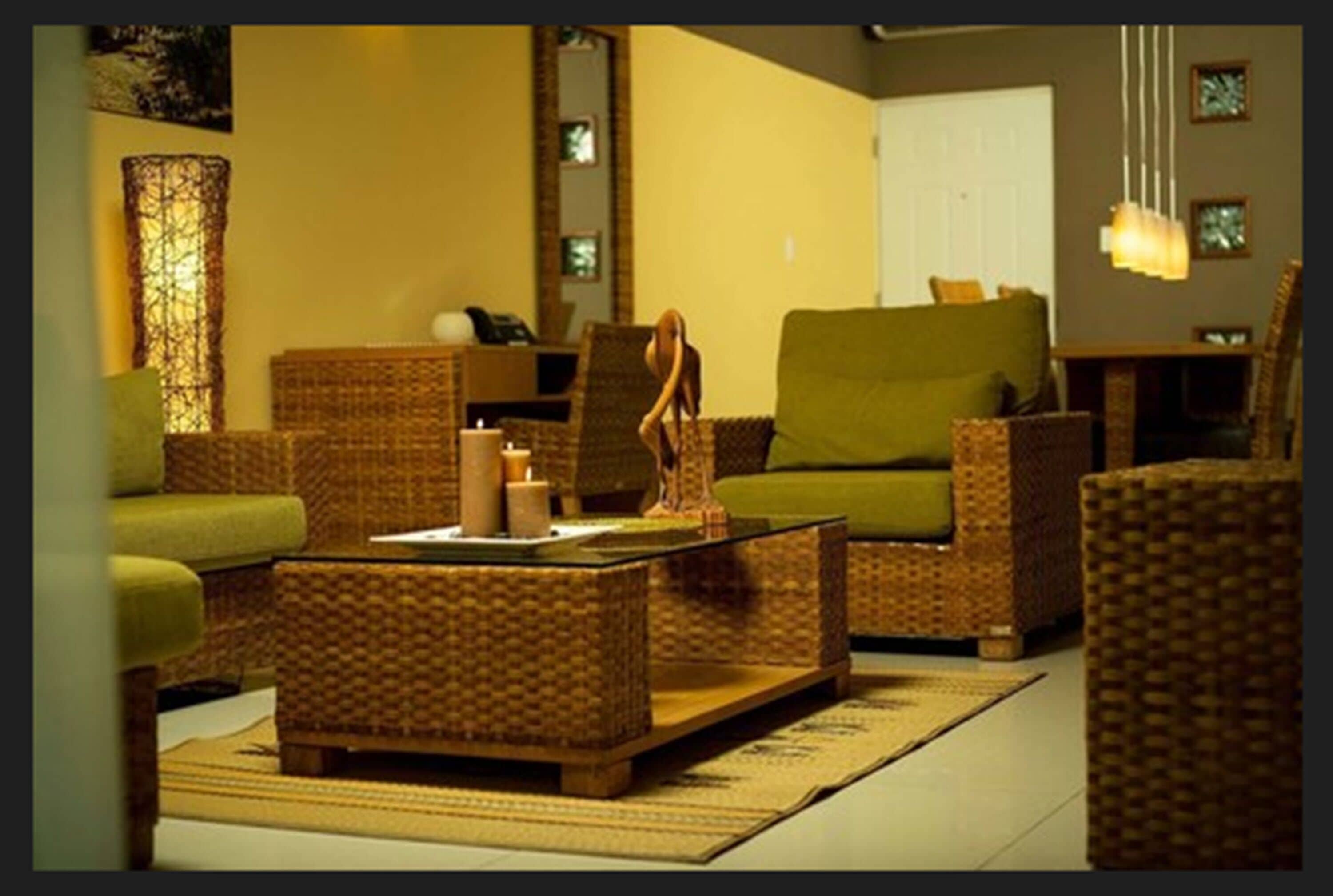 A cozy living room with wicker furniture, a green sofa, and a coffee table with decorative items.