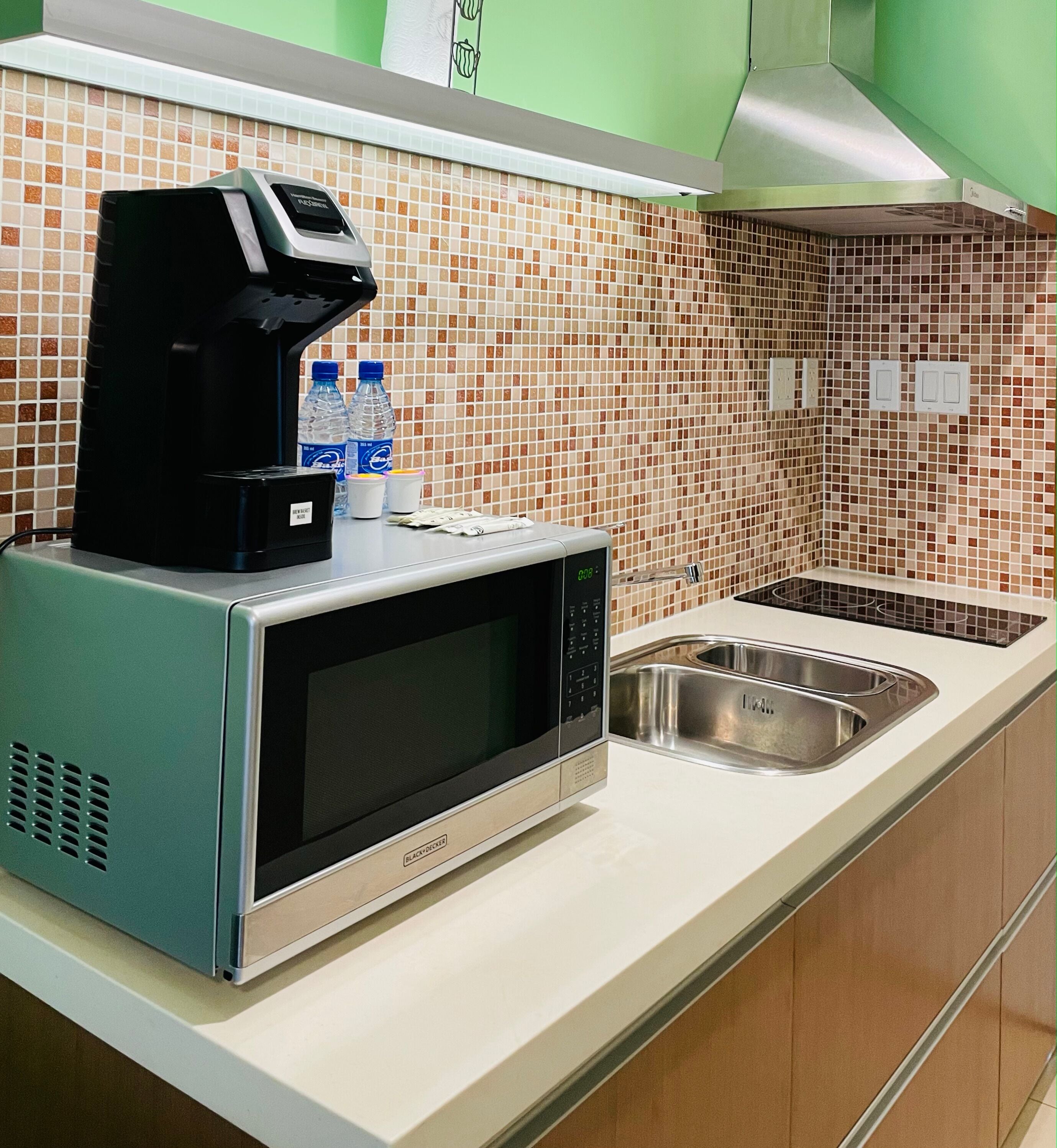 A kitchen with a microwave, a coffee maker, and a sink.