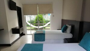A hotel room with two beds, a TV, and a view of a hammock outside. - Ocean Blue Hotel (Manglaralto)