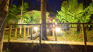 Une terrasse en bois, dotée de rampes de protection, entourée d’une végétation luxuriante et de palmiers.