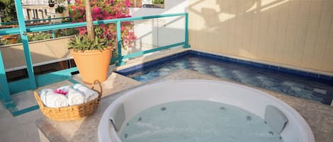 Un jacuzzi con zona de piscina con azulejos, una cesta de mimbre con toallas y una planta en maceta.