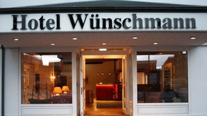 The entrance of Hotel Wünschmann with a visible reception desk and a red interior. - Hotel Wünschmann (Sylt)